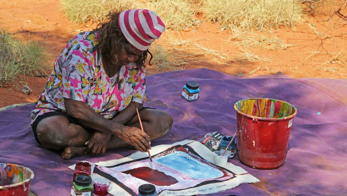 Bugai Whyoutler painting at Kunawarritji in 2013. Photograph courtesy Martumili Artists.